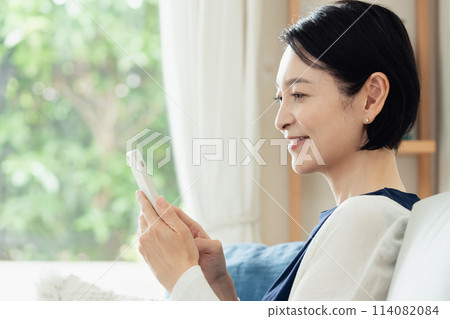 在客廳操作智慧型手機的家庭主婦 114082084