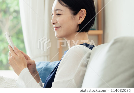 在客廳操作智慧型手機的家庭主婦 114082085