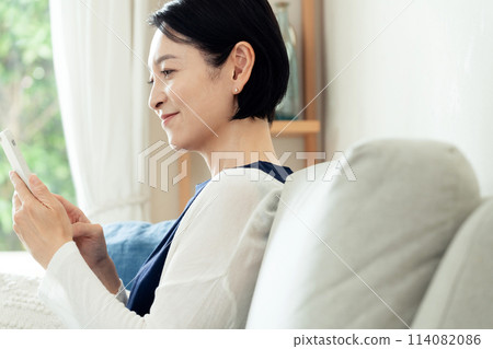 在客廳操作智慧型手機的家庭主婦 114082086