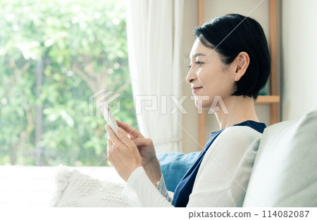 在客廳操作智慧型手機的家庭主婦 114082087