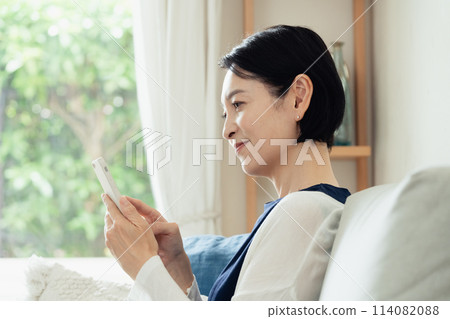在客廳操作智慧型手機的家庭主婦 114082088