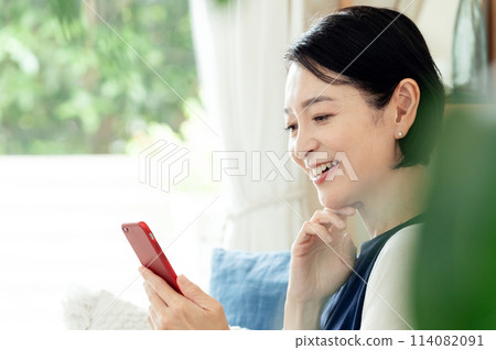 在客廳操作智慧型手機的家庭主婦 114082091