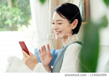 在客廳操作智慧型手機的家庭主婦 114082099