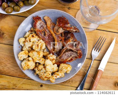 Dish with fried lamb and stewed cauliflower on served table 114082611