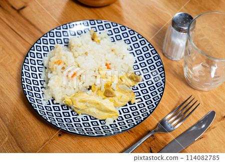 Baked chicken thighs served with rice on plate 114082785