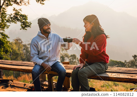man and woman are sitting on a wooden bench, smiling at each other 114082812