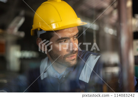 Close-up shot of an employee wearing a hard hat while working in an industrial factory 114083242