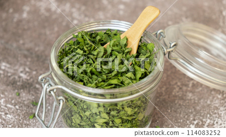 Glass jar with green dry parsley. Vegetarian bio organic salad herb healthy eating. Home garden immunity-boosting herbs. Seasonal harvest Glass jar with green dry parsley. Vegetarian bio organic salad herb healthy eating. Home garden immunity-boosting herbs. Seasonal harvest 114083252
