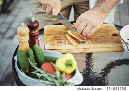 Unrecognizable man slicing sweet bell pepper for salad Unrecognizable man slicing sweet bell pepper for salad 114083868