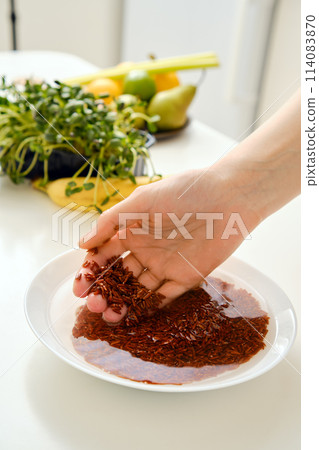 Closeup view of female hand rinsing pink rice in a bowl 114083870