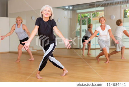 Positive aged woman practicing vigorous dance movements Positive aged woman practicing vigorous dance movements 114084441