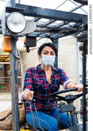 Female worker in protective mask of materials working on forklift truck 114084545