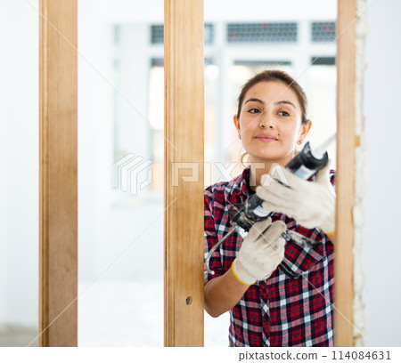 Positive woman using spray foam around doorway Positive woman using spray foam around doorway 114084631