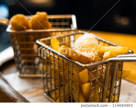 Two baskets of finger food french fries and chicken nuggets on a table 114084903
