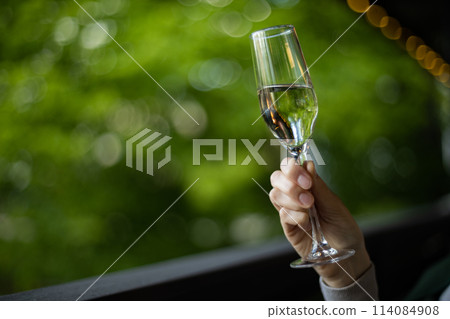 Hand holding glass of champagne, reflecting in automotive mirror 114084908