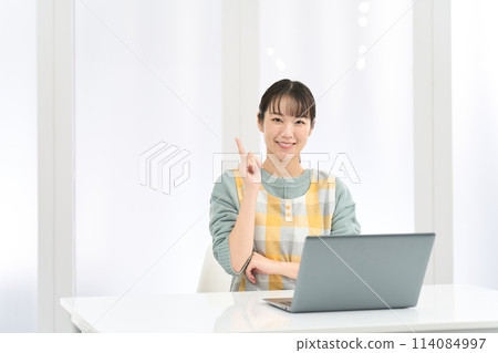 一位穿著圍裙的女士在電腦上工作時想出了好主意 114084997