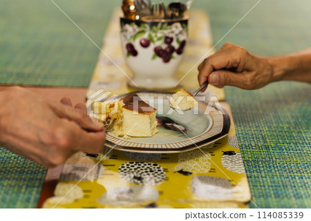 Senior couple hands with spoon eating burnt cheesecake. Senior couple hands with spoon eating burnt cheesecake. 114085339