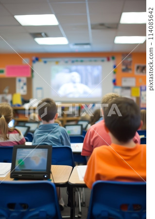 School children watching an educational film in a classroom with personal laptops. 114085642
