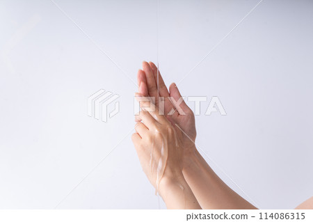 Part of a woman's hand with oil dripping from above 114086315