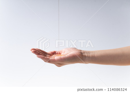 Parts of a woman's hand dripping with oil 114086324