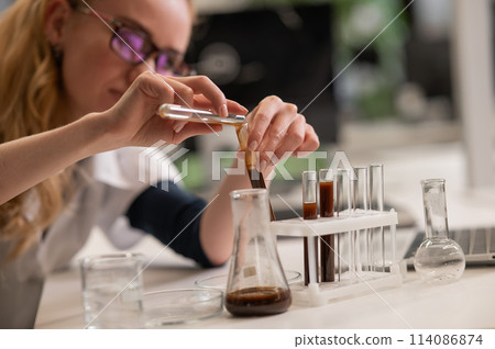 Caucasian woman in a medical gown doing laboratory experiments.  114086874