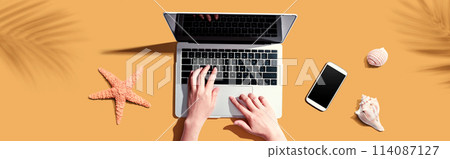 Person using a laptop computer with shells and starfish 114087127