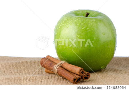 Ripe green apple with cinnamon sticks Ripe green apple with cinnamon sticks 114088064