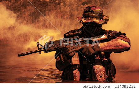 A bearded soldier performs a surveillance task in the water, walking through a swamp, surrounded by mist fog, rifle at the ready for imminent threats, colorized toned shot A bearded soldier performs a surveillance task in the water, walking through a swamp, surrounded by mist fog, rifle at the ready for imminent threats, colorized toned shot 114091232