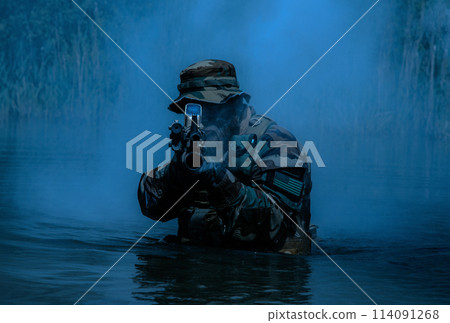 A bearded soldier performs a surveillance task in the water, walking through a swamp, surrounded by night fog, rifle at the ready for imminent threats, colorized toned shot A bearded soldier performs a surveillance task in the water, walking through a swamp, surrounded by night fog, rifle at the ready for imminent threats, colorized toned shot 114091268