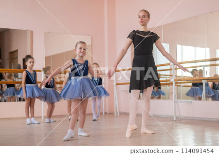 Children's ballet school. Caucasian woman teaching ballet to little girls. Children's ballet school. Caucasian woman teaching ballet to little girls. 114091454