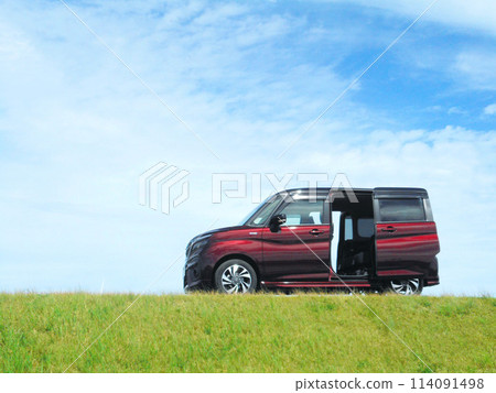 A small car with its sliding doors open parked on top of a hill A small car with its sliding doors open parked on top of a hill 114091498