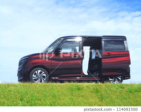 A small car with its sliding doors open parked on top of a hill A small car with its sliding doors open parked on top of a hill 114091500