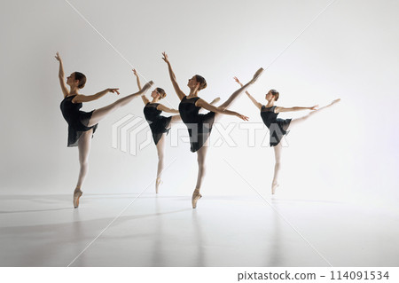 Inspiration. Young teen girls, graceful ballerinas in back costumes standing on pointe, training, performing complex ballet moves 114091534