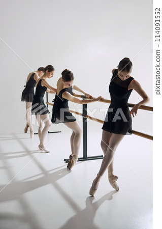 Discipline and focus. Tender teen girls, ballet dancers in black costumes attending dance class, training against grey studio background Discipline and focus. Tender teen girls, ballet dancers in black costumes attending dance class, training against grey studio background 114091552