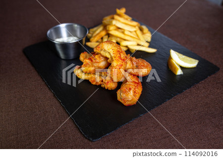 fish in batter with sauce and fries on a black plate fish in batter with sauce and fries on a black plate 114092016