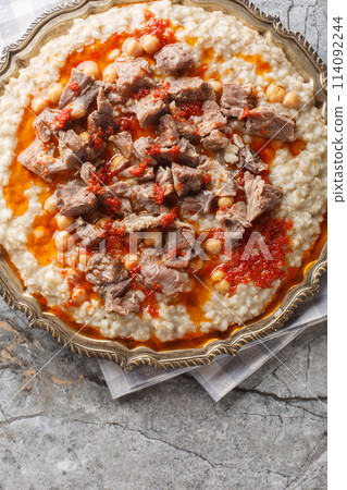 Keskek or kashkak, kashkek, or keske, is a ceremonial lamb meat and wheat chickpeas stew closeup on the plate. Vertical top view 114092244