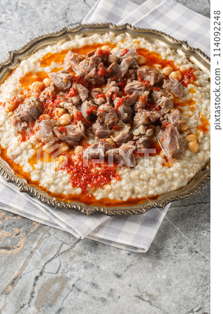 Keskek or kashkak, kashkek, or keske, is a ceremonial lamb meat and wheat chickpeas stew in Turkish, Iranian, Greek, Armenian and Balkan cuisines closeup on the plate. Vertical 114092248