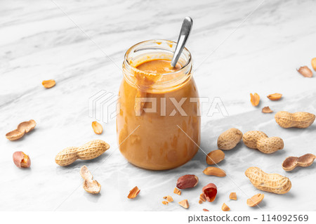 Peanut butter in glass jar on white marble table Peanut butter in glass jar on white marble table 114092569