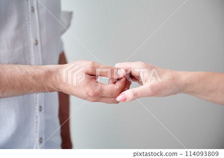 Close up of two hands engaging in delicate touch. Man's and woman's hands on white neutral background. Husband holding hand of his lovely wife. Concept of love, intimacy, support, and trust. 114093809