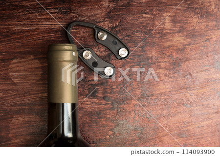 Wine bottle and bottle opener on wooden background Wine bottle and bottle opener on wooden background 114093900