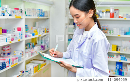 Asian woman pharmacist filling prescription in pharmacy drugstore 114094969