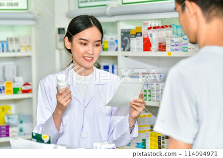 Female pharmacist holding medicine giving advice to customer in pharmacy store 114094971