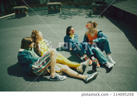 Group of friends spending time on city rooftop. Wearing trendy mix of streetwear, featuring denim and vibrant hues, reflecting their dynamic personalities. Group of friends spending time on city rooftop. Wearing trendy mix of streetwear, featuring denim and vibrant hues, reflecting their dynamic personalities. 114095208