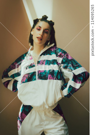 Young beautiful girl standing confidently in stylish 90s inspired tracksuit, trendy makeup and playful hair buns. Modern retro fashion portrait 114095265