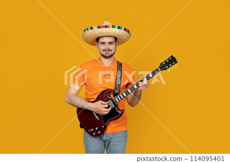 Attractive young guy playing guitar in mexican hat Attractive young guy playing guitar in mexican hat 114095401