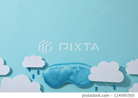 Sleep mask, pills and paper clouds on blue background, space for text 114095505
