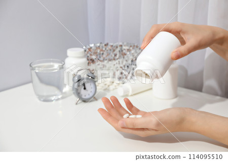 Jar of pills in hands, glass, sleep mask and alarm clock on light background 114095510