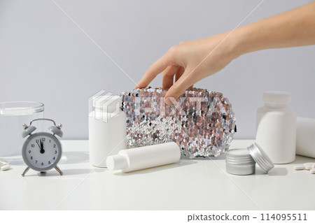 Jars of pills, glass, sleep mask, alarm clock and hand on light background Jars of pills, glass, sleep mask, alarm clock and hand on light background 114095511