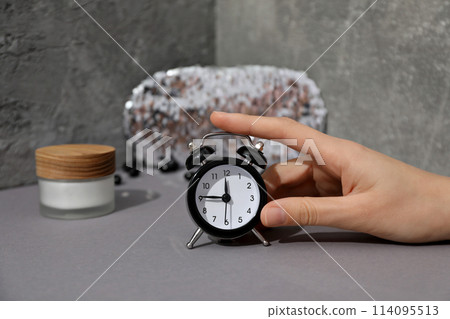 Sleep mask, jar of cream, alarm clock and hand on gray background 114095513