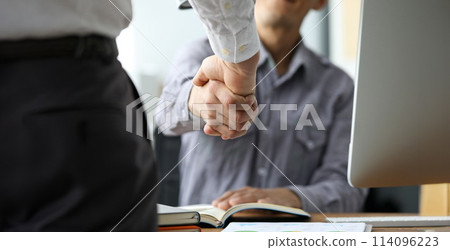 Two male clerks shaking hands at workplace close-up Two male clerks shaking hands at workplace close-up 114096223